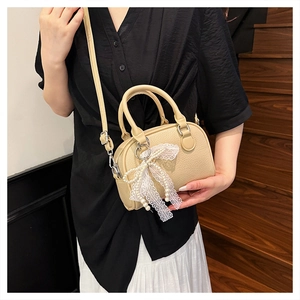 Close-up of beige litchi grain Boston bag featuring a pearl and lace bow decoration