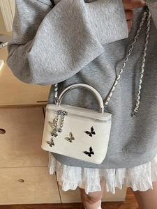 White mini box bag with silver bow details and metallic top handle on casual model