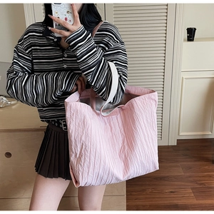 Pink pleated texture tote bag styled with a casual striped shirt and pleated skirt
