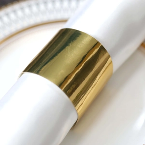 Detail of a shiny gold napkin ring on a white napkin and a decorative dinner plate
