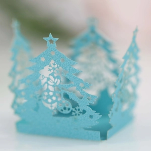 Detail of laser-cut light blue paper lantern with hollow Christmas tree patterns