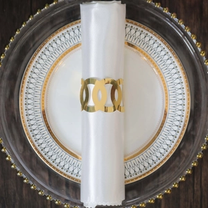 Macro detail of golden metal napkin ring with triple hollow circles on white silk