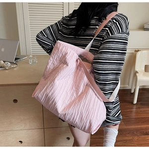 Detail view of pink pleated tote bag with stylish shoulder strap and logo patch