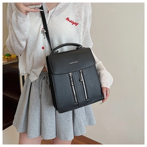 Detail of the black leather crossbody bag with decorative zippers and a top handle