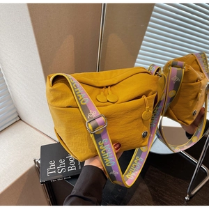Detail of yellow canvas crossbody bag featuring colorful wide jacquard shoulder strap