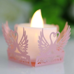 Detailed view of pink laser-cut swan paper candle holder wrap with a warm LED tea light
