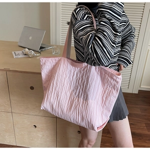 Detail of pink tote bag with textured crinkle fabric and round brand patch close-up