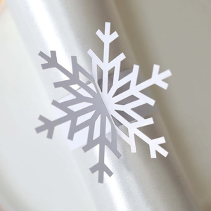 Detailed view of a white snowflake napkin ring on a satin napkin for Christmas table decor