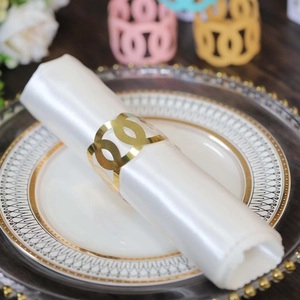 Polished gold hollow geometric metal napkin ring set on elegant white satin cloth