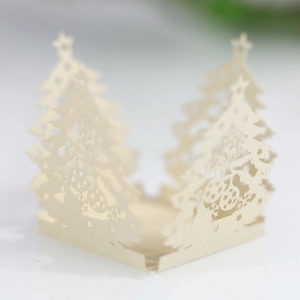 Macro view of laser-cut Christmas tree pattern on ivory cream paper candy box