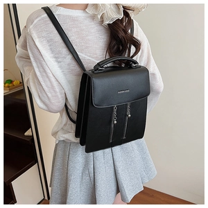 Detail of black faux leather backpack with silver chains and dual zipper accents