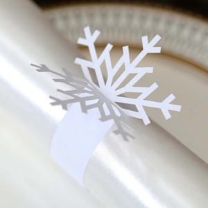 Detailed macro view of white paper snowflake napkin rings with precision cutouts for Christmas