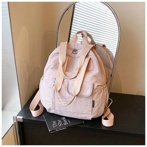 Close-up of light pink nylon backpack with adjustable side pockets and zipper details