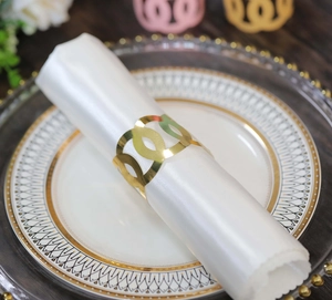 Close-up of golden geometric napkin ring with hollow design on white fabric