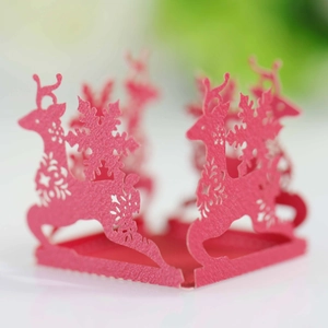 Detailed macro view of laser-cut red Christmas cupcake wrapper with reindeer and snowflakes