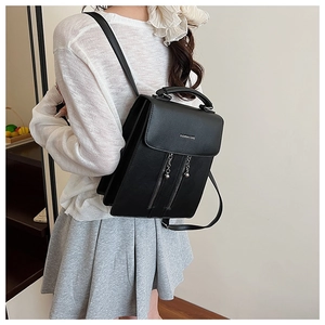Detail view of a black faux leather backpack with vertical zippers and fashion logo lettering