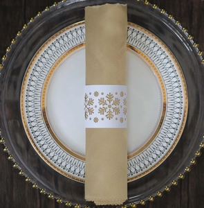 Macro view of a white laser-cut snowflake napkin ring on champagne gold cloth