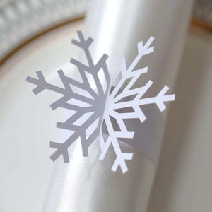 Macro detail of laser-cut white snowflake napkin ring on elegant satin napkin