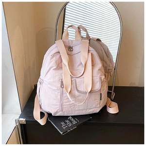 Detail of light pink nylon backpack featuring dual handles and vertical zipper pocket
