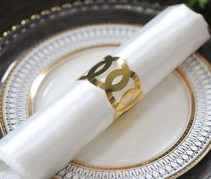Detail of elegant gold hollow geometric napkin ring on a white silk napkin