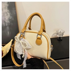 Detail of cream lychee texture Boston bag with yellow handle and pearl bow charm