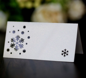 Detail of white pearlescent snowflake place card on a dark wooden table background