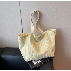 Close-up of pale yellow tote bag with vertical pleated texture and JUMAITU brand logo