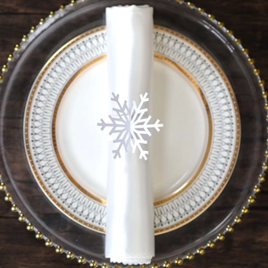 Detailed view of a white snowflake napkin ring on a white satin napkin for Christmas