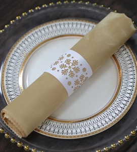 Detail of white hollow snowflake napkin ring on a gold napkin for festive table settings