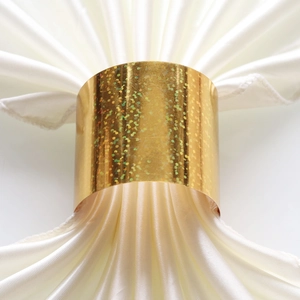Macro shot of glittery golden napkin ring with sparkling sequins on white satin