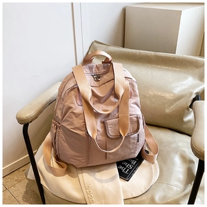 Detailed view of light pink nylon backpack with wide straps and dual metal zippers
