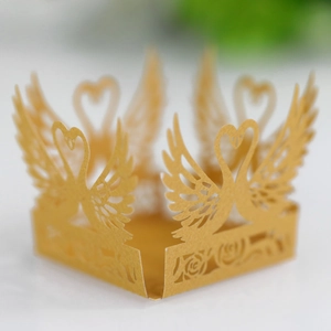 Macro view of gold laser-cut swan heart favor box with intricate floral hollow patterns