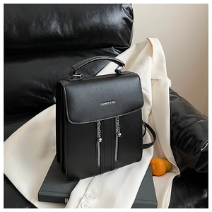 Detail shot of black pebbled leather square bag with decorative zippers and chain pendants
