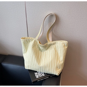 Close-up of JUMAITU yellow tote bag showing fine vertical pleated texture and embossed logo