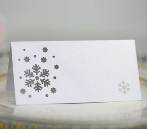 Detail of laser-cut snowflake on pearlescent white folded table name card for Christmas