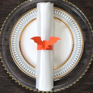 Macro shot of bright orange bat napkin ring on white fabric for Halloween table decor