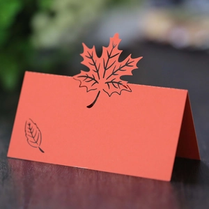 Laser-cut orange maple leaf place card featuring intricate hollow-out design and fold-up stand