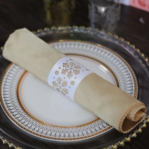 Detailed laser-cut snowflake napkin ring in white paper on a festive ceramic dinner plate