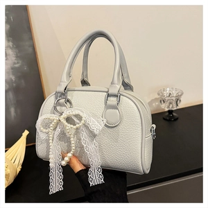 Detail of lychee textured handbag featuring elegant white lace bow and pearl decoration
