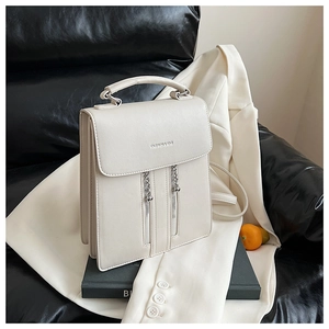 Detail of cream white PU backpack featuring decorative vertical zippers and silver chains