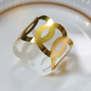 Macro shot of gold hollow geometric napkin ring on a white plate for elegant table decor
