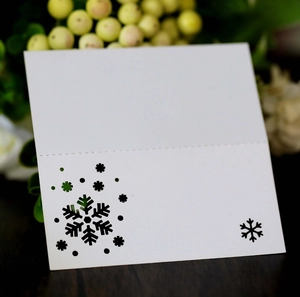 Macro detail of white laser-cut snowflake place card on a rustic wood texture surface