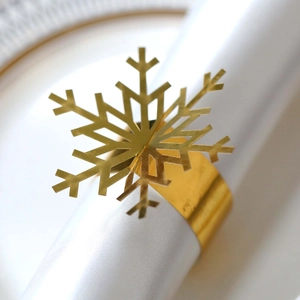 Golden Christmas snowflake napkin ring with intricate hollow metal cutouts for table setting