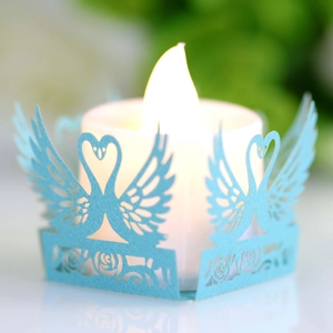 Detail of light blue laser-cut candle shade with swan and rose hollow pattern and LED candle