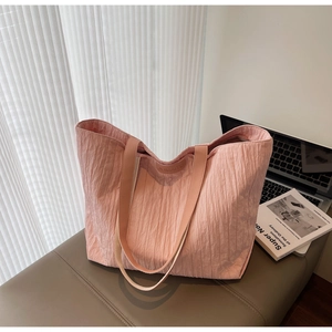 Close-up of pink tote bag showing wrinkled texture, leather handles, and inner brand tag