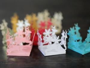 Detail view of laser-cut reindeer and snowflake hollow designs on colorful favor boxes