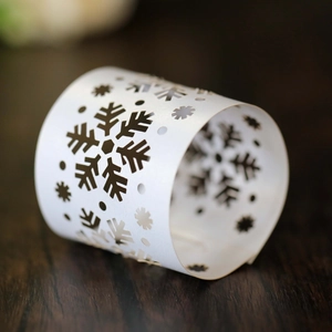 Close-up of laser-cut white snowflake napkin ring on a textured dark wood surface