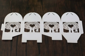 Detailed laser-cut white paper wedding favor box with romantic tree and heart pattern