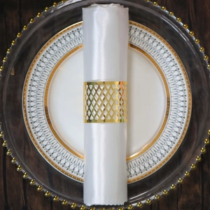 Detail showing a gold hollow lattice napkin ring on a white fabric napkin for weddings