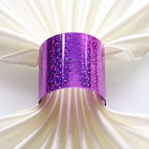 Close-up of sparkling purple glitter napkin ring on a folded white satin cloth